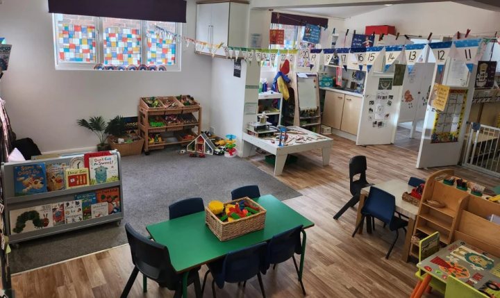 Empty nursery playroom with a book corner and activity tables.